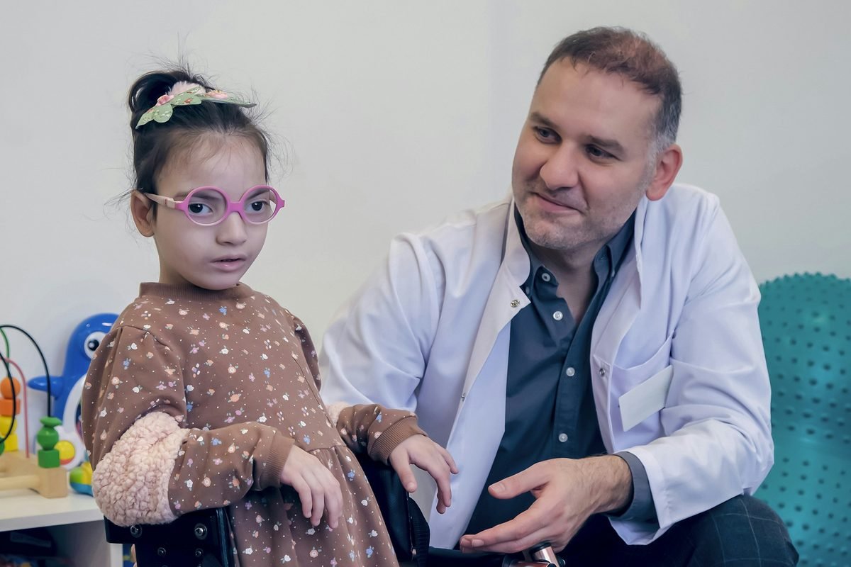 A therapist supporting a young patient using a walking frame